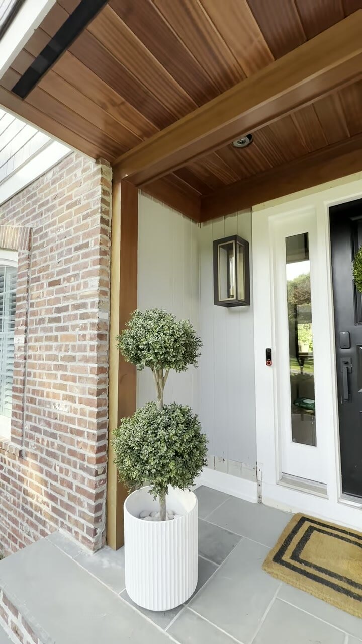 Covered porch with a stained tongue-and-groove wood ceiling and brick columns.